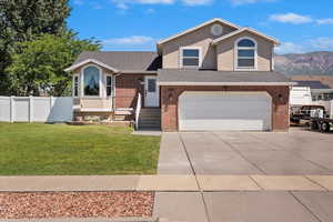 View of front of property with driveway, a garage, brick siding, and a mountain view
