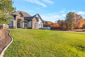View of home's exterior featuring stone siding and a lawn
