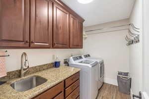 Laundry area featuring separate washer and dryer, cabinet space, light wood-style floors, and baseboards