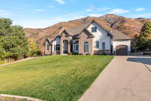 French country home featuring stone siding, stucco siding, a garage, concrete driveway, and a front lawn