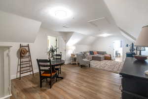 Dining room featuring lofted ceiling, light wood-style floors, attic access, and baseboards