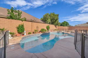 View of swimming pool featuring a fenced backyard, a pool with connected hot tub, and a patio area
