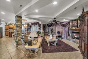 Living area with decorative columns, a fireplace, ceiling fan, light tile patterned floors, and recessed lighting