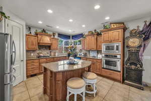 Kitchen featuring appliances with stainless steel finishes, custom exhaust hood, a center island, tasteful backsplash, and recessed lighting