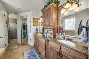 Bathroom with a stall shower, double vanity, tile patterned floors, a garden tub, and a spacious closet
