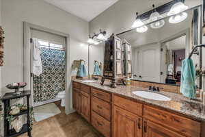 Full bathroom with double vanity, toilet, tile patterned floors, and a shower with curtain
