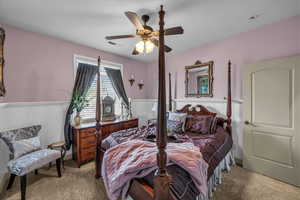 Bedroom featuring wainscoting, light colored carpet, and a ceiling fan