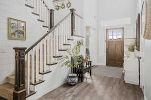 Foyer with dark wood-type flooring, stairs, a towering ceiling, and baseboards