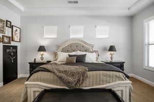 Carpeted bedroom featuring baseboards and multiple windows