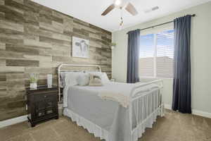 Bedroom featuring wood walls, an accent wall, carpet floors, baseboards, and ceiling fan