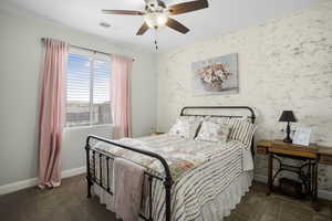 Carpeted bedroom featuring an accent wall, baseboards, and a ceiling fan