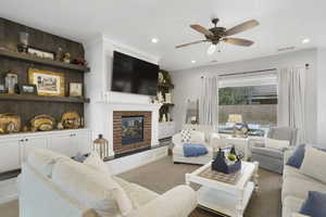 Carpeted living area with ceiling fan, recessed lighting, and a fireplace
