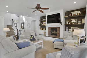 Carpeted living area with a ceiling fan, arched walkways, recessed lighting, stairs, and built in features