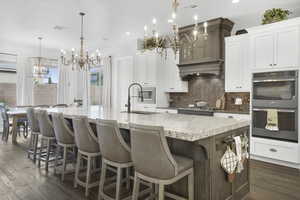 Kitchen featuring a chandelier, a sink, stainless steel appliances, backsplash, and dark wood-type flooring