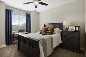 Bedroom with dark colored carpet, baseboards, and ceiling fan