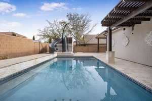 View of swimming pool featuring a water slide, a fenced backyard, a pergola, and a patio area