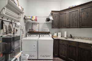 Laundry room featuring washing machine and clothes dryer, cabinet space, and wood finished floors