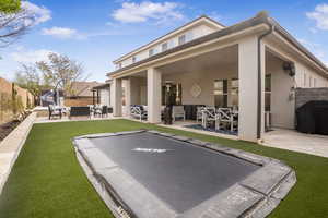 Rear view of house with an outdoor living space, stucco siding, a patio area, and a trampoline