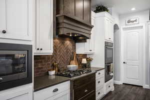 Kitchen featuring built in microwave, dark countertops, gas stovetop, dark wood-style flooring, and tasteful backsplash
