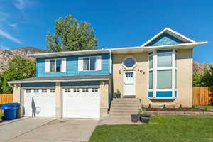 Bi-level home featuring an attached garage, driveway, a mountain view, and brick siding