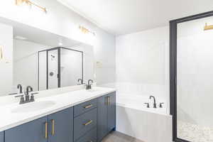 Bathroom featuring a stall shower, a bath, double vanity, and tile patterned flooring