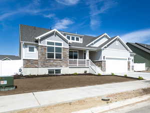 Craftsman house with stone siding, board and batten siding, an attached garage, and driveway