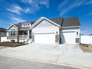 View of front of property featuring stone siding, a garage, board and batten siding, concrete driveway, and a residential view