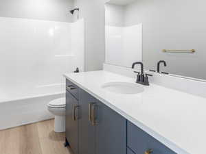Bathroom featuring vanity, toilet, bathing tub / shower combination, and wood finished floors