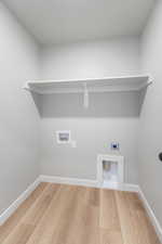 Laundry area with hookup for an electric dryer, wood finished floors, hookup for a washing machine, and baseboards
