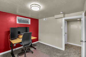 Carpeted office space featuring a textured ceiling and baseboards