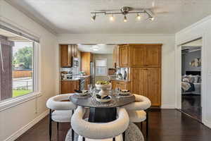 Dining space featuring plenty of natural light, dark wood finished floors, a textured ceiling, and crown molding