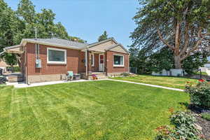 View of front of home with brick siding, a patio, and roof with shingles