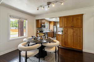 Dining area with dark wood-style flooring, ornamental molding, and a textured ceiling