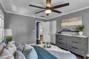 Bedroom with wood finished floors, baseboards, ceiling fan, ornamental molding, and a textured ceiling