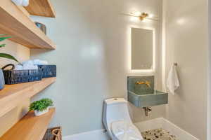 Bathroom featuring toilet, baseboards, and a sink