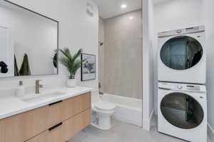 Bathroom with stacked washer and clothes dryer, vanity, toilet, bathing tub / shower combination, and recessed lighting