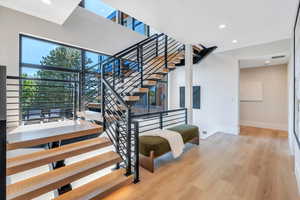 Stairway featuring baseboards, wood finished floors, and recessed lighting