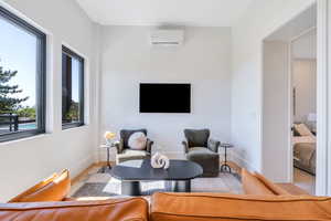 Sitting room featuring a wall mounted AC, wood finished floors, and baseboards