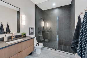 Full bathroom with vanity, toilet, marble look tile flooring, a walk in shower, and recessed lighting