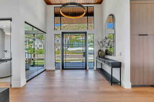 Foyer featuring wood ceiling, a high ceiling, healthy amount of natural light, wood finished floors, and baseboards
