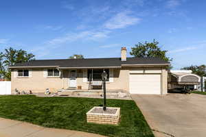 Ranch-style home with a garage, brick siding, concrete driveway, and a chimney