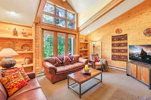 Living room with picture windows, french doors to deck and vaulted ceiling,