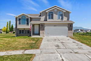 View of front facade with a front yard, an attached garage, concrete driveway, brick siding, and a shingled roof