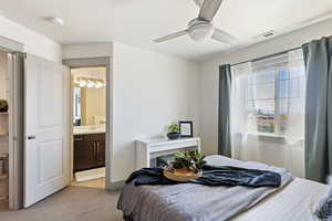 Bedroom featuring light colored carpet, a sink, ensuite bath, and ceiling fan