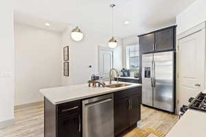 Kitchen featuring stainless steel appliances, a sink, light countertops, pendant lighting, and recessed lighting