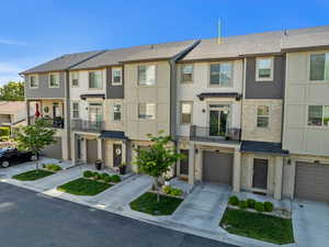 Townhome / multi-family property featuring a garage, driveway, and stone siding