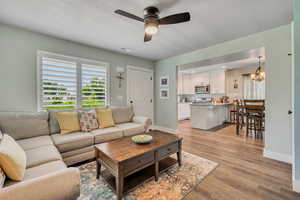 Living area with a ceiling fan, a chandelier, healthy amount of natural light, and light wood-style floors