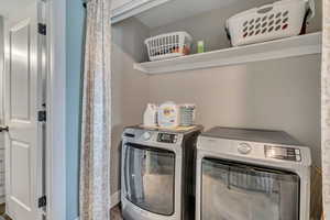 Washroom with washing machine and clothes dryer and wood finished floors