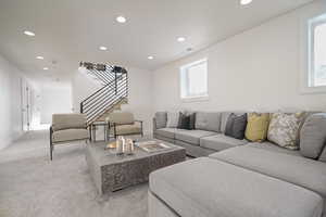 Living room with recessed lighting, stairway, light colored carpet, and baseboards