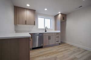 Kitchen featuring dishwasher, a sink, recessed lighting, light wood-type flooring, and baseboards